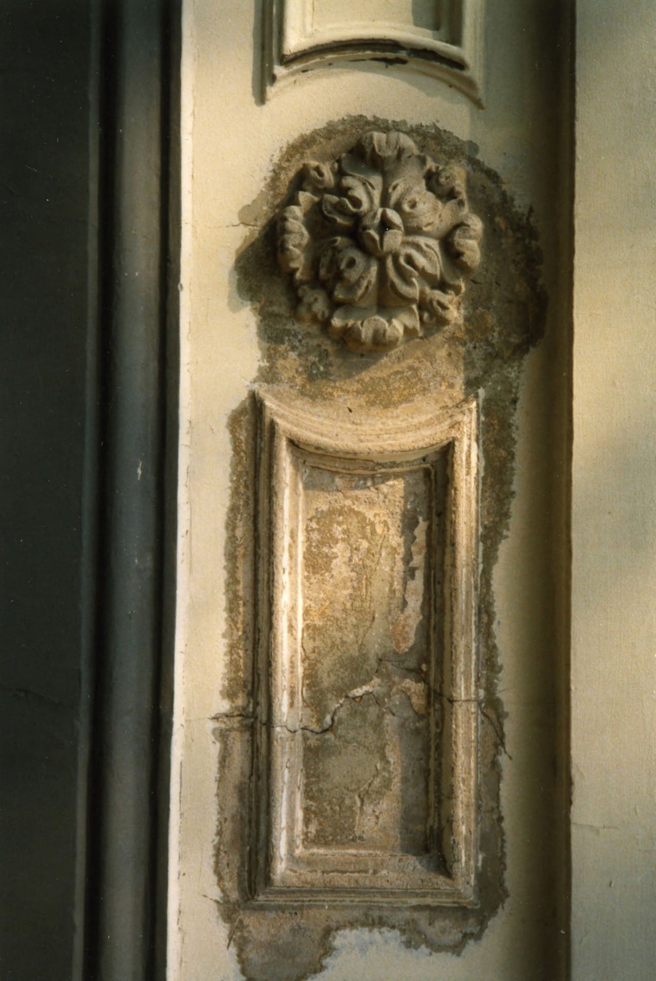 Kleurenfoto uit 1988 van een verweerd gepleisterd ornament op een pilaster.