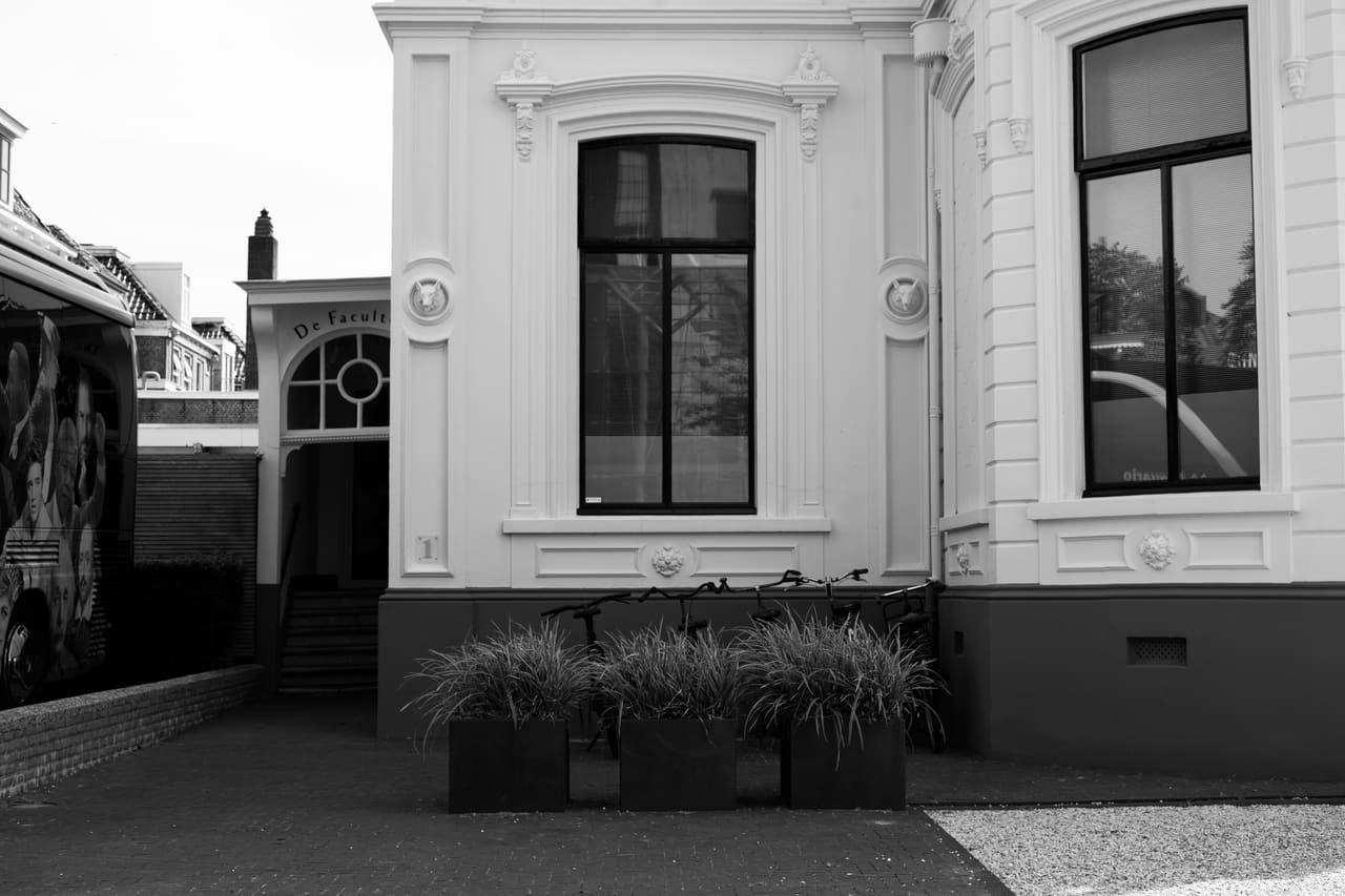 Zwart-witopname van de zijgevel van Villa Sophialaan met hoge vensters en plantenbakken op het pad.