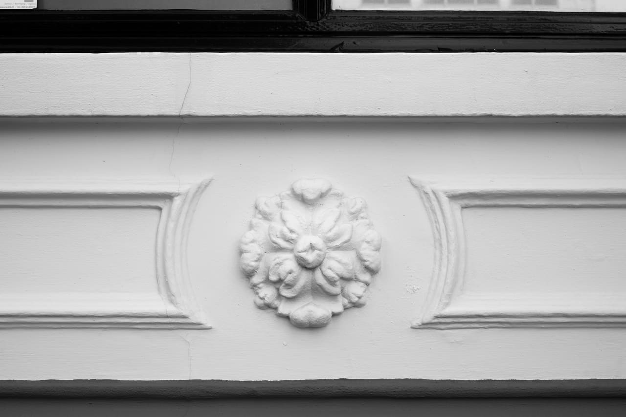Detailopname van een bloemvormig rozet in een horizontale gevellijst.